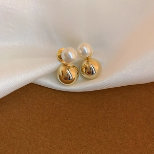 Detailed close-up of gold-plated pearl stud earrings on elegant white silk background
