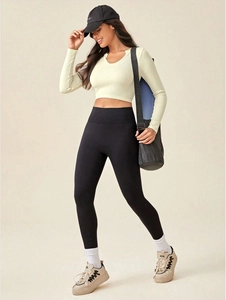 Detail of a beige ribbed long sleeve crop top and black yoga leggings on model