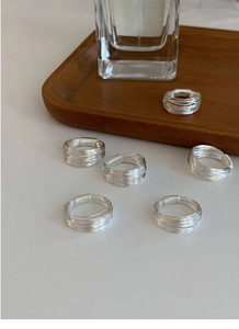 Minimalist multi-layer silver rings displayed on a wooden tray for a refined look