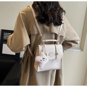Detail of cream multi-functional mini backpack with gold hardware and plush bear charm