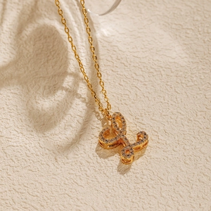 Detailed close-up of 18K gold plated letter L pendant with pavé crystals on stone texture