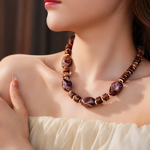 Dettaglio delle perle in resina ambrata con distanziali dorati su collana girocollo retrò
