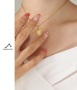 Detail of a gold butterfly pendant necklace with cubic zirconia on a model collarbone