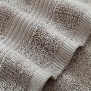 Macro detail of high-density soft cotton towel loops with elegant striped satin borders