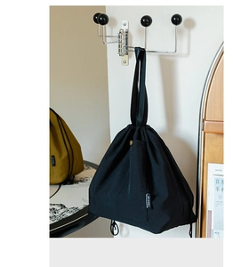 Detail of waterproof black nylon lunch bag with drawstring closure and metal snap pocket