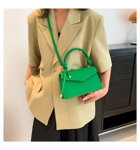 Detailed view of green textured shoulder bag featuring geometric embossing and hardware