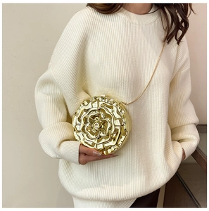 Detail of 3D gold rose clutch bag with metallic texture and sleek chain strap