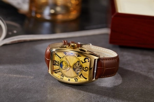 Close-up of golden tonneau mechanical watch with brown leather strap and moon phase dial