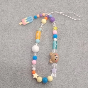 Detailed shot of beaded phone strap with brown bear, ice cream charms and USA beads