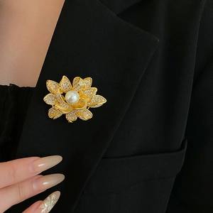 Detail of flower brooch with gold plating, sparkling crystals, and central pearl on a blazer