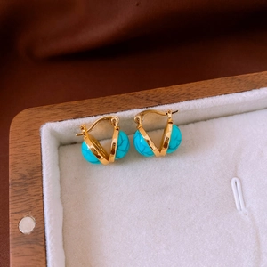 Detail of vintage gold V-shaped earrings with blue resin round beads on white velvet