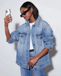 Detail shot of oversized light blue washed denim jacket with flap pockets and metal buttons
