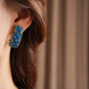 Gros plan de boucles d'oreilles bohèmes rectangulaires dorées avec cristaux bleus