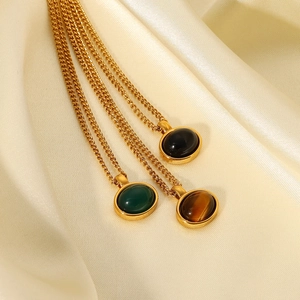 Detailed view of oval natural stone pendants in green and tiger eye on gold chain