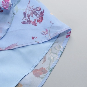 Detail eines hellblauen Blumenkleides mit Fokus auf die Naht und Chiffon-Stoff