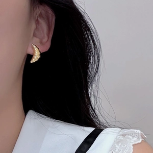 Golden crescent moon earrings with croissant texture shown on a female model