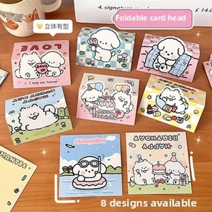 Foldable cartoon dog birthday cards in pastel colors on wooden surface detail view
