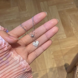 Close-up of double-layer silver heart necklace with crystal pendant held in hand