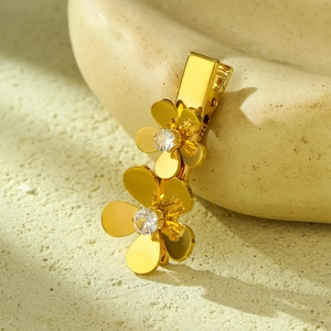 Detailed close-up of golden floral hair clip with zircon petals on a stone surface