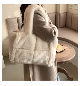 Spacious beige plush tote bag in soft faux fur shown on a model in a warm interior setting