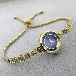 Detail of gold bracelet watch with blue dial, floral rhinestones and adjustable slider clasp