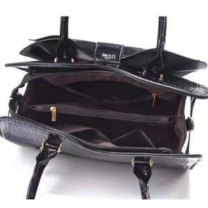 Internal view of black crocodile pattern handbag with multi-compartment lining and zippers