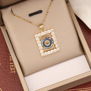 Nahaufnahme des 18K Gold-Augenanhängers mit Zirkonia-Inlay auf champagnerfarbenem Samt