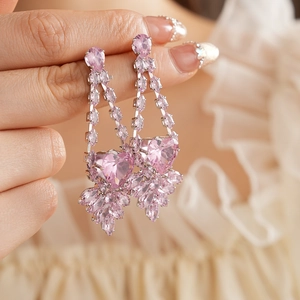 Détail de boucles d'oreilles en cristal rose en forme de cœur sur tissu beige doux