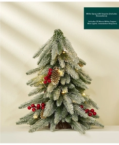 Detail of mini snowy Christmas tree with red berries, pine cones and warm LED lights