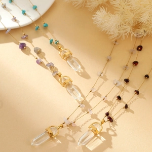 Close-up of golden necklaces with colorful natural stone beads and hexagonal crystal pendants