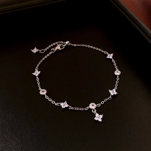 Close-up of silver-plated four-leaf flower bracelet with zircons on dark leather