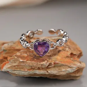 Macro detail of heart-cut purple amethyst ring with silver chain band on stone