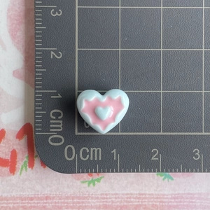 Macro detail of a 1.3cm blue and pink heart-shaped resin accessory on a ruler