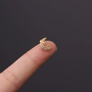 Macro detail of gold-plated moon and star stud earring with inlaid sparkling zircons