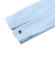 Detailed close-up of sky blue cotton linen shirt cuff with vintage brown button