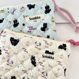 Detail of quilted floral cotton pouches with rhombus stitching and woven zipper puller