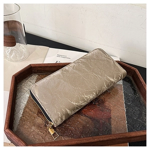 Detail of champagne gold faux leather wallet with pleated texture on a wooden tray