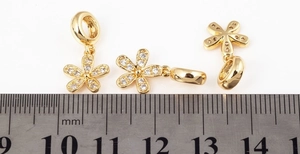 Detail view of gold-plated flower charms with scale showing 11mm width measurement