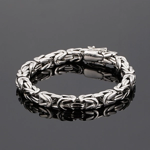 Close-up of a silver Byzantine stainless steel bracelet with a clasp on black reflection