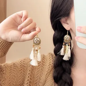 Detail of bohemian shell tassel earrings with vintage flower texture on gold finish