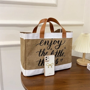 Linen tote bag with leather straps and 'enjoy the little things' print on wood table