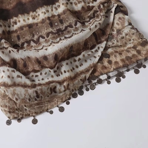 Detail of ethnic style fabric with brown white texture and metal coin tassels