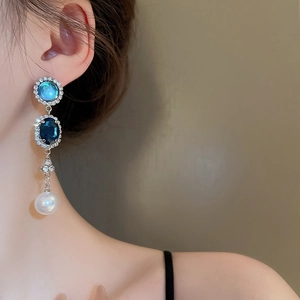 Détail de boucles d'oreilles en perles et pierres bleues portées par un mannequin