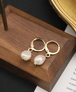 Detail view of baroque pearl earrings with gold metal hoops on a vintage display