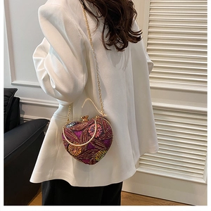 Detail of a heart-shaped evening bag with colorful sequin floral embroidery and gold chain