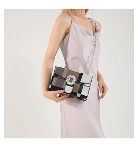 Close-up of stylish plaid handbag featuring a sparkling rhinestone buckle and silver chain
