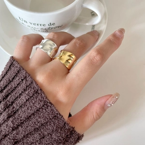 Detail of irregular wave rings in gold and silver finish worn with a cozy autumn sweater