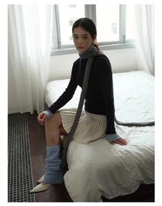 Detail view of extra long light gray knit scarf paired with a stylish navy blue turtleneck sweater