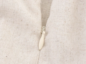Vue macro détaillée de la texture du tissu en lin crème et du zip invisible assorti