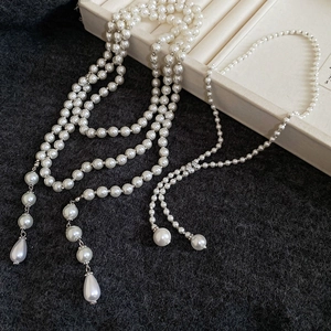 Macro detail of multi-layered pearl necklace with teardrop pendant on jewelry tray